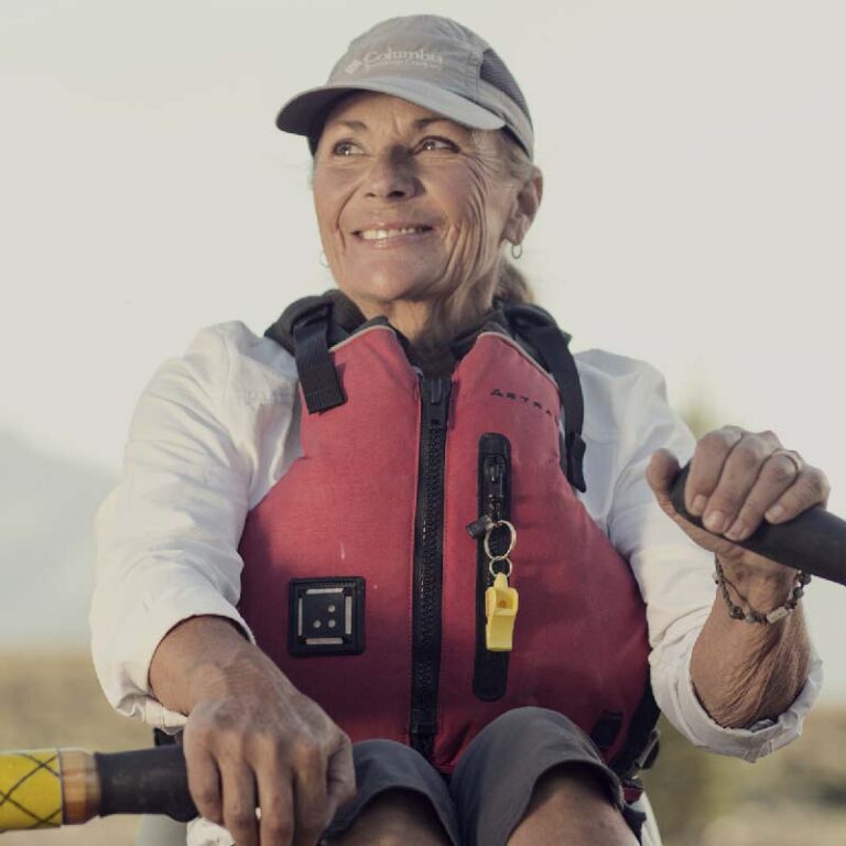 photo of an older woman smiling while riding a canoe