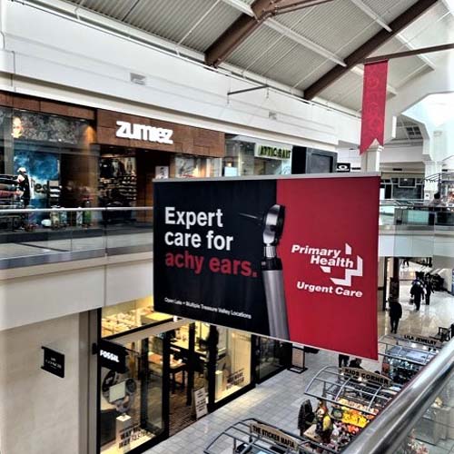 Banner hanging in mall with image of otoscope and text that reads "Expert care for achy ears"