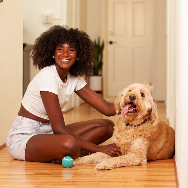 Woman and her dog sit in a hallway for Pets Best advertising photo shoot