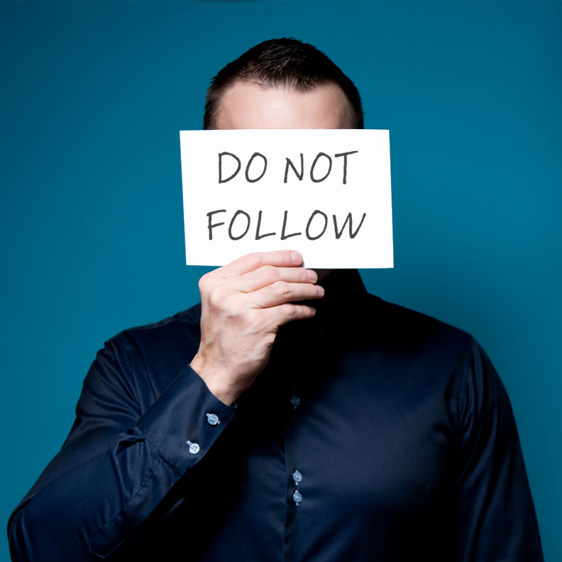 Man covering his face with a "Do Not Follow" sign