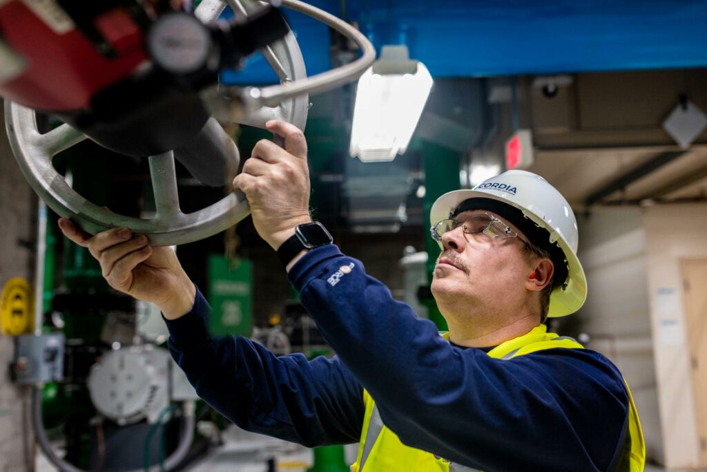 A Cordia employee in a factory turning a wheel. 