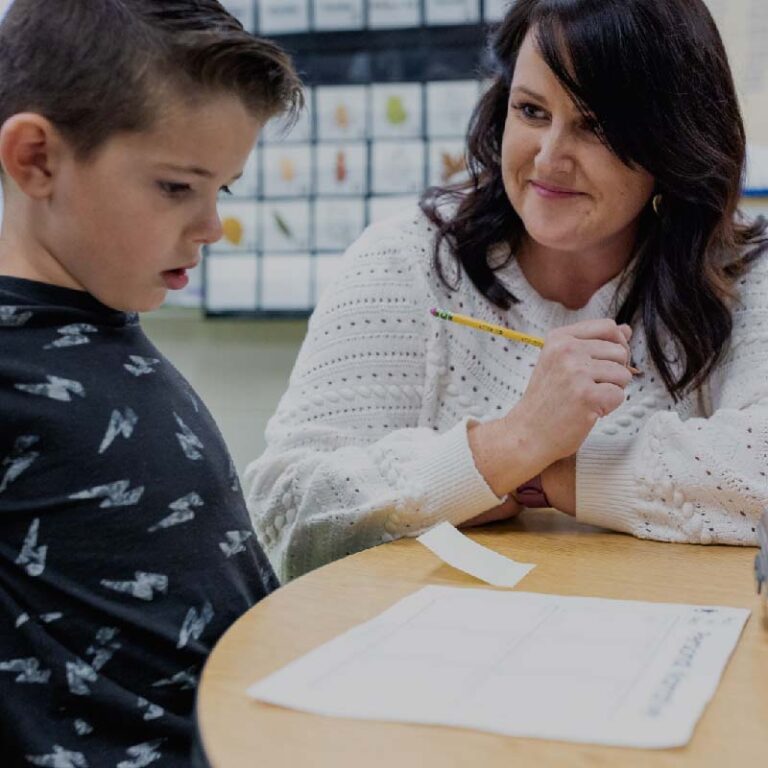 photo of a female teacher assisting a student with vowels