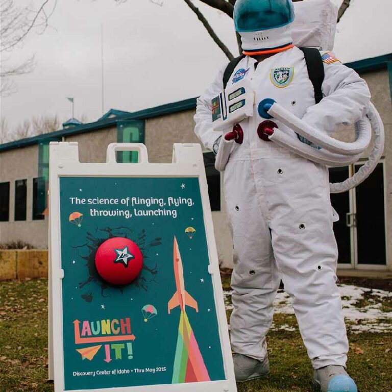 photo of an astronaut standing next to a promotional sign