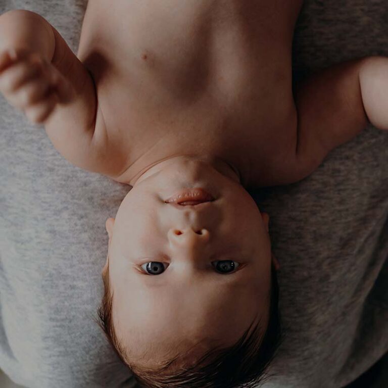 photo of a baby with blue eyes laying on a mother's lap