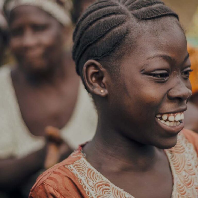 photo of one smiling woman in focus, and another woman in the background