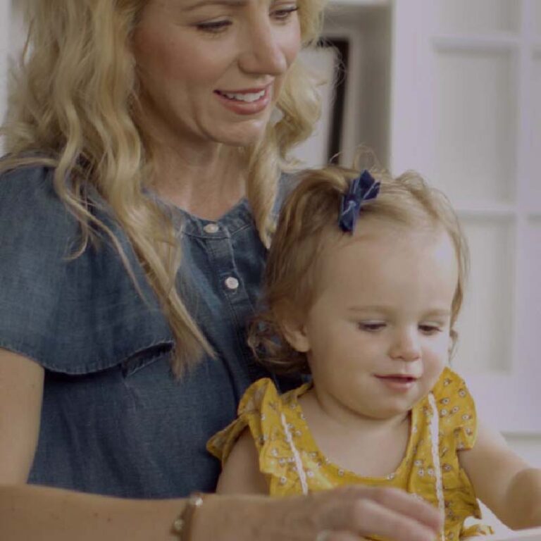 photo of blonde mother reading a book for her daughter