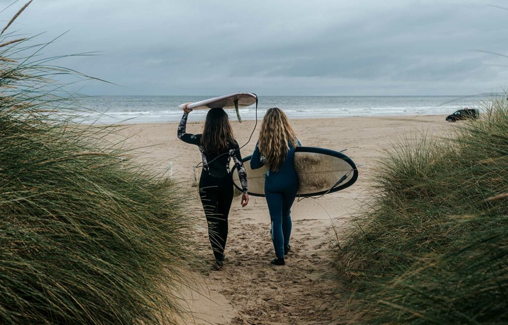 Salty Sea Sisters bringing surfboards down to the ocean