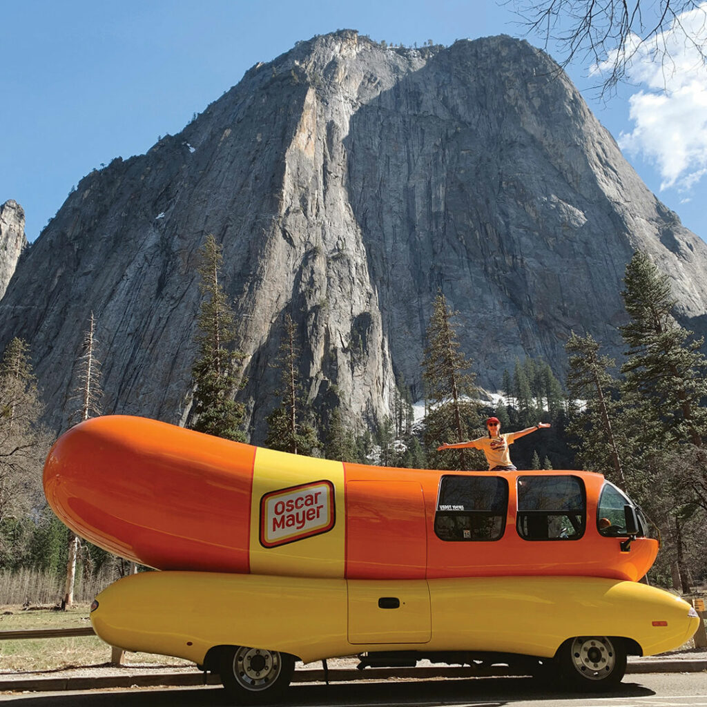 Photograph of the oscar meyer weiner mobile in front of a towering mountain