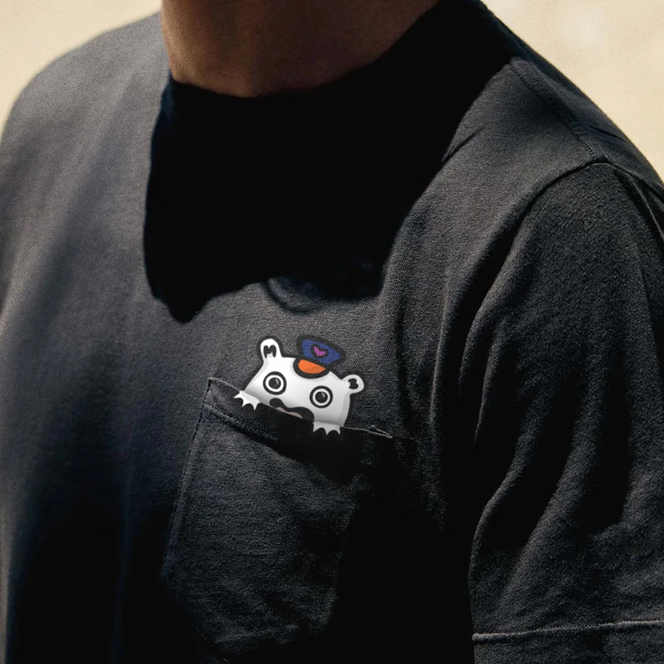 A man wearing a shirt with a front pocket, Lil Rider is peeking out of the pocket